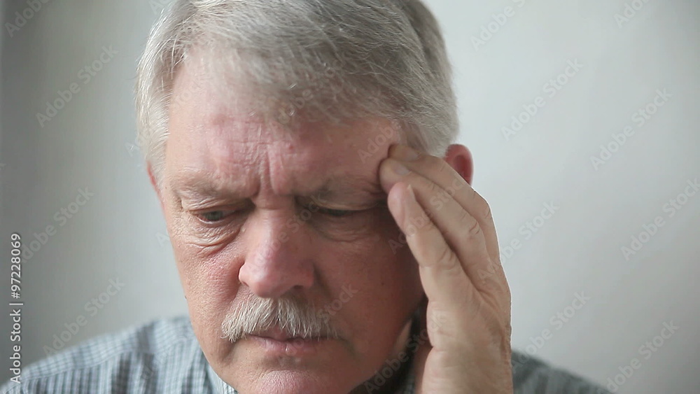 A senior man massages his temple as he suffers from a bad headache A senior man massages his temple as he suffers from a bad headache