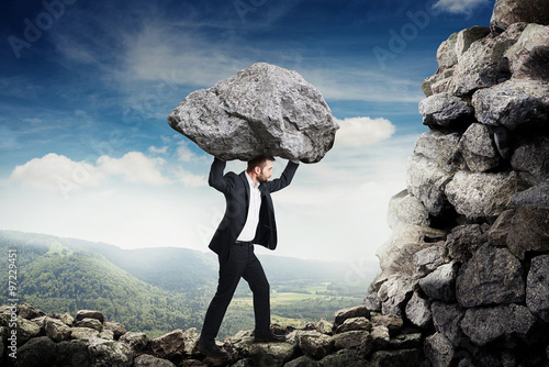 Fotografie man in formal wear holding big stone and walking