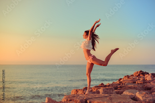 Joyful slim lady in bikini jumping standing on cliff background 