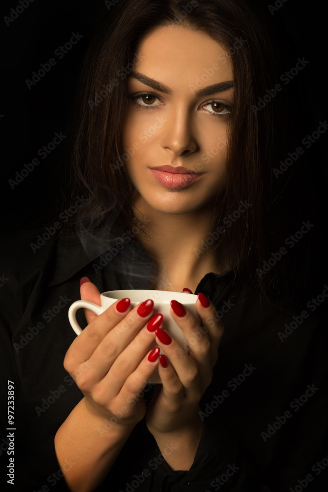 Young brunette woman with cup of coffee on a dark background Young brunette woman with cup of coffee on a dark background