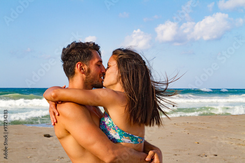Young couple kissing at the beach in late afternoon.