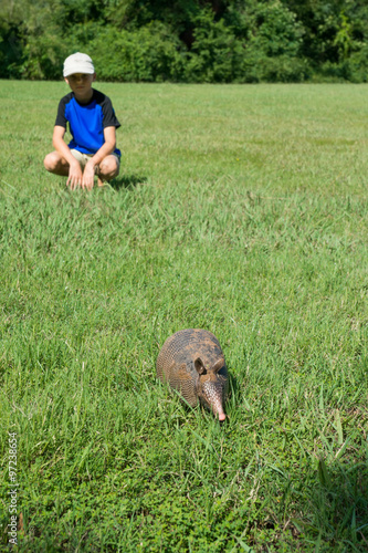 Boy hurt looking at a fleeing into the forest armadillo. Focus o