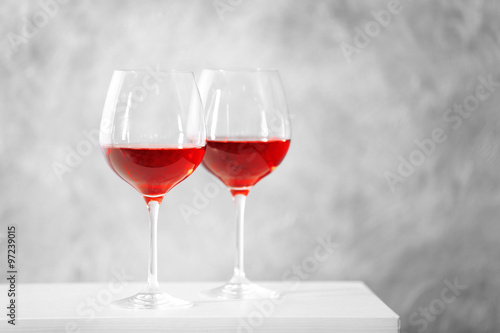 Two glasses of red wine with christmas accessories on grey wall background