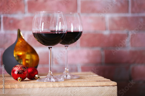 Two glasses of wine with christmas toys on wall background
