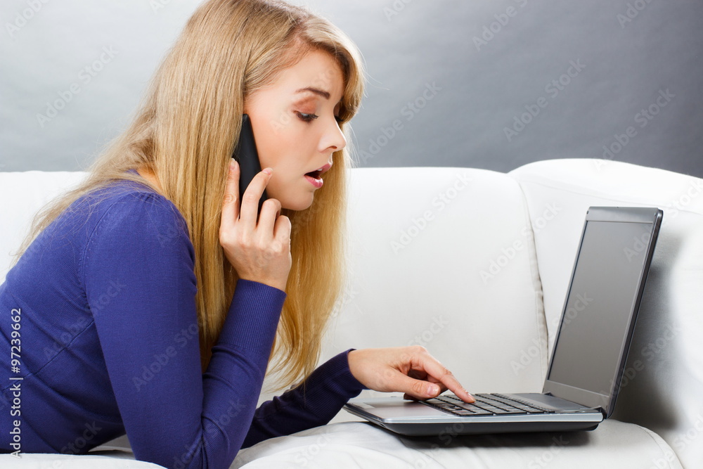 Woman talking on mobile phone and using laptop lying on sofa, modern technology Woman talking on mobile phone and using laptop lying on sofa, modern technology