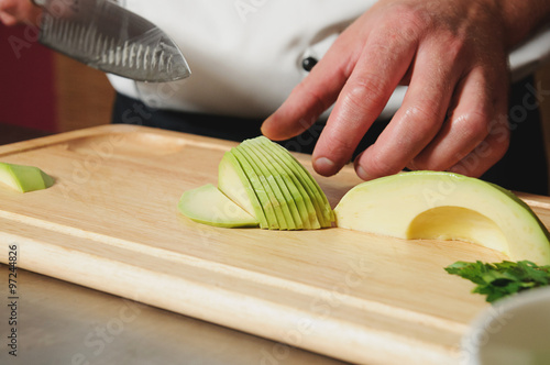 chef cutting avocado on table
