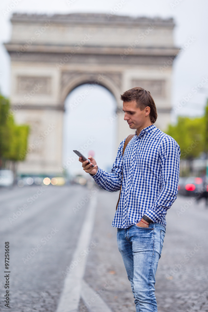 Young caucasian man holding a phone on the Champs Elysees in Paris