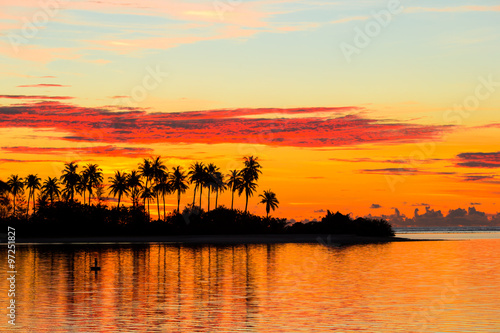 Beautiful sunset with dark silhouettes of palm trees and amazing cloudy sky in Indian island