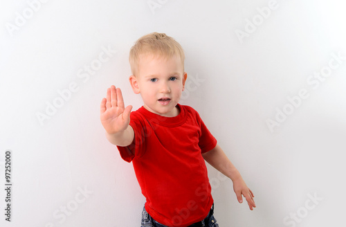 little boy in red shirt showing stop sign