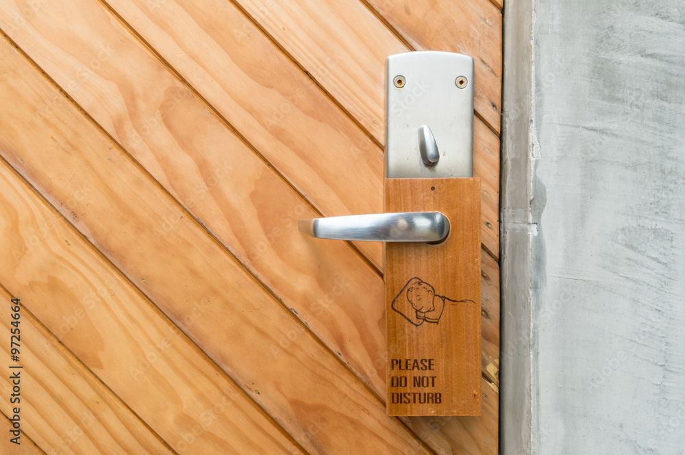 Closeup brown wooden door with do not disturb label at the handle background Closeup brown wooden door with do not disturb label at the handle background