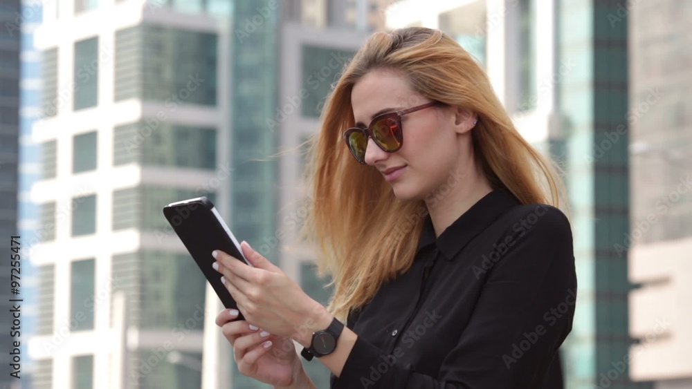 Beautiful businesswoman standing on the street and working on tablet Beautiful businesswoman standing on the street and working on tablet