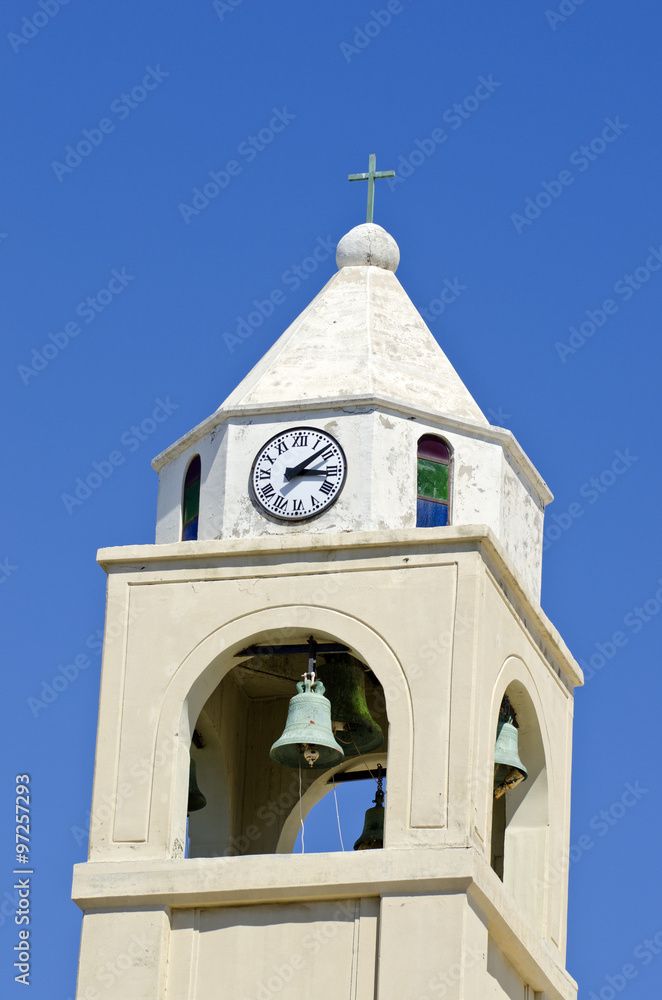 Church bellfry with clock against blue sky
