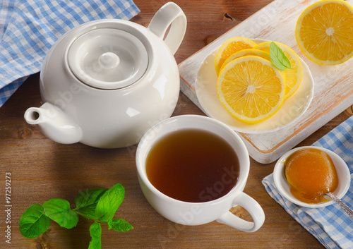 Teapot and cup with tea with lemon and mint