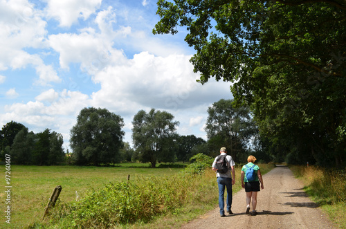 Man and woman hiking on a gravel road next to a meadow © lembrechtsjonas