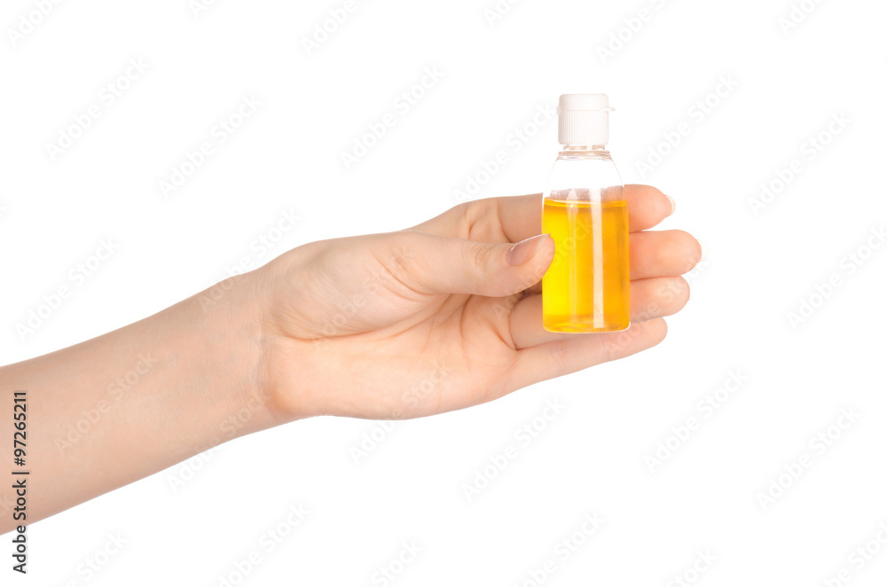 Beauty and health topic: a woman's hand holding a small yellow bottle of shampoo in the studio isolated on a white background Beauty and health topic: a woman's hand holding a small yellow bottle of shampoo in the studio isolated on a white background