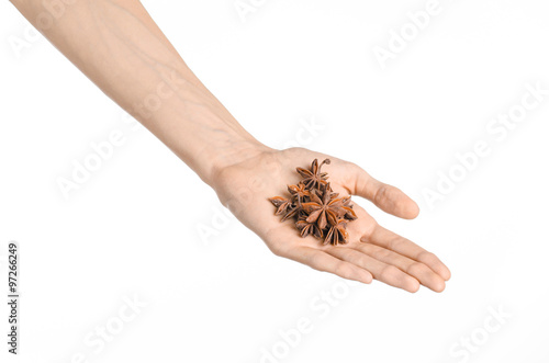 Spices and cooking theme: man's hand holding star anise isolated on white background in studio