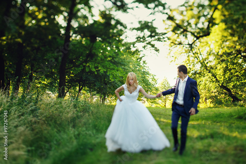 Sexual beautiful elegant bride and handsome groom walking in the forest