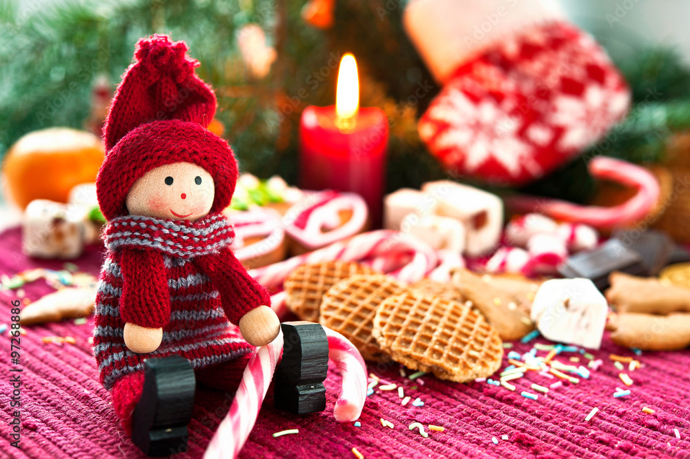 Wooden smiling doll with sweets on christmas background with can