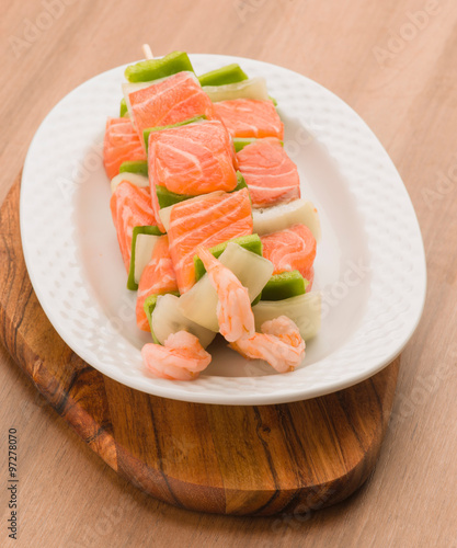 skewers of salmon and vegetables in white porcelain tray on eleg