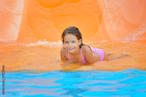 Adorable toddler girl on water slide at aquapark