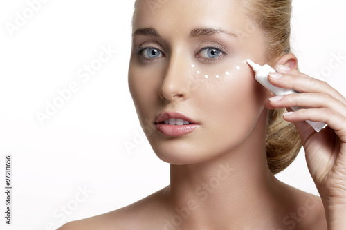 young beautiful woman applying creme on her skin