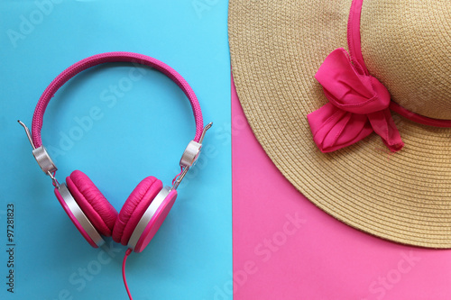 Pretty straw hat and pink headphones on colorful background