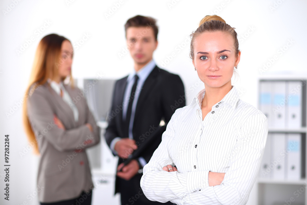 Pretty businesswoman in office with colleagues in the background Pretty businesswoman in office with colleagues in the background