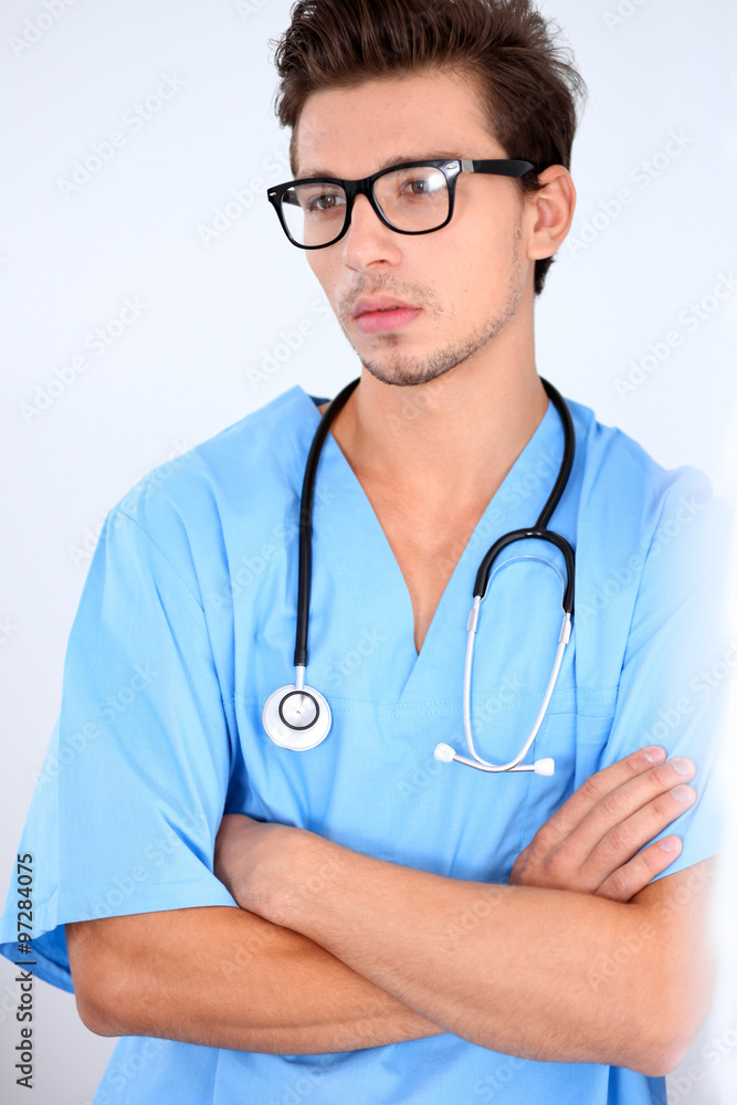Attractive male doctor standing near the wall, crossed arms Attractive male doctor standing near the wall, crossed arms