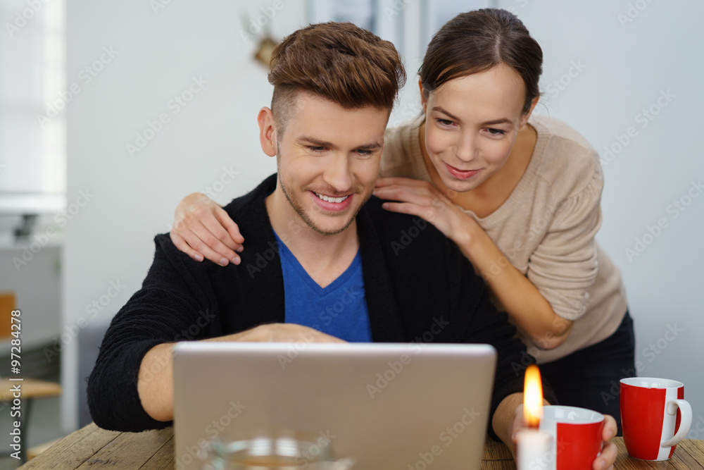 glückliches paar sitzt am esstisch und schaut auf notebook glückliches paar sitzt am esstisch und schaut auf notebook
