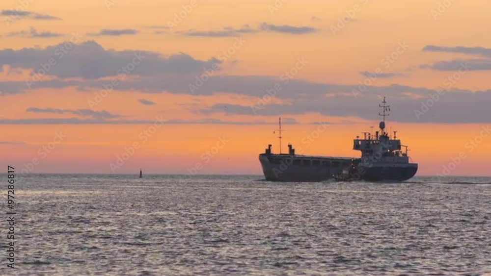 Maritime pilot convoys a bulk carrier leaving port into sea during vivid sunset Maritime pilot convoys a bulk carrier leaving port into sea during vivid sunset