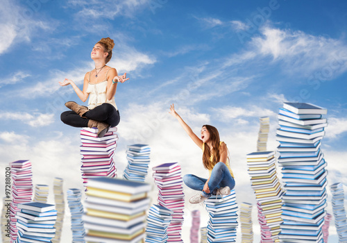 competitive young woman sitting on a books pile ascending to the