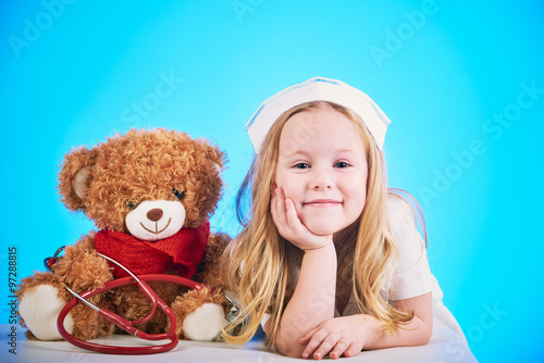 Billede på lærred Beautiful nurse examiner little sick brown teddy bear.