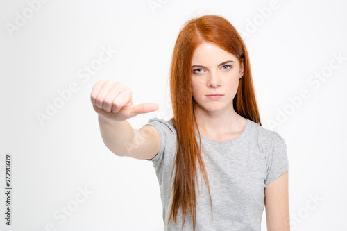 Serious unhappy woman pointing away with thumb