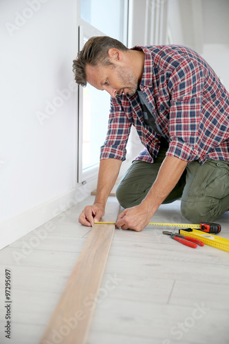 Cheerful man at home installing new wooden floor