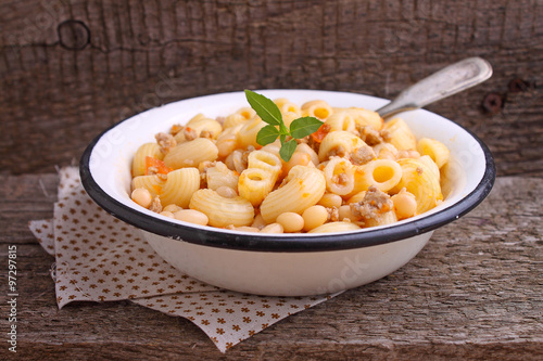 pasta with meat and beans in a white bowl on the old wooden background