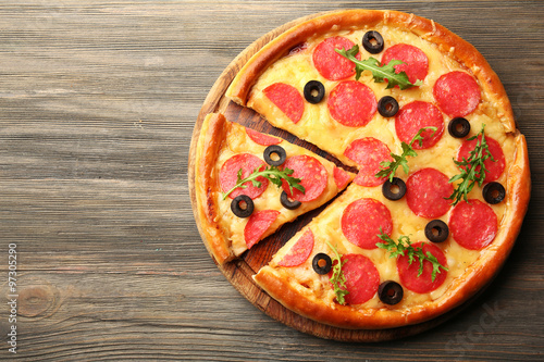 Hot tasty pizza with salami and olives on wooden background