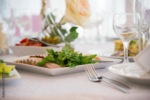 Restaurant tableware dishes. Serving the dining table. A dish of snacks on the table. Cutlery and plate of food on white tablecloths. Forks and spoons on the holiday table. Menu for one person.