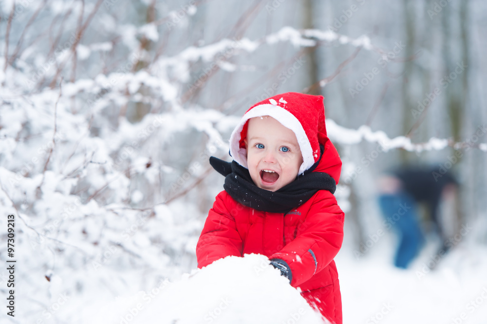 The kid builds a snowman from snow.