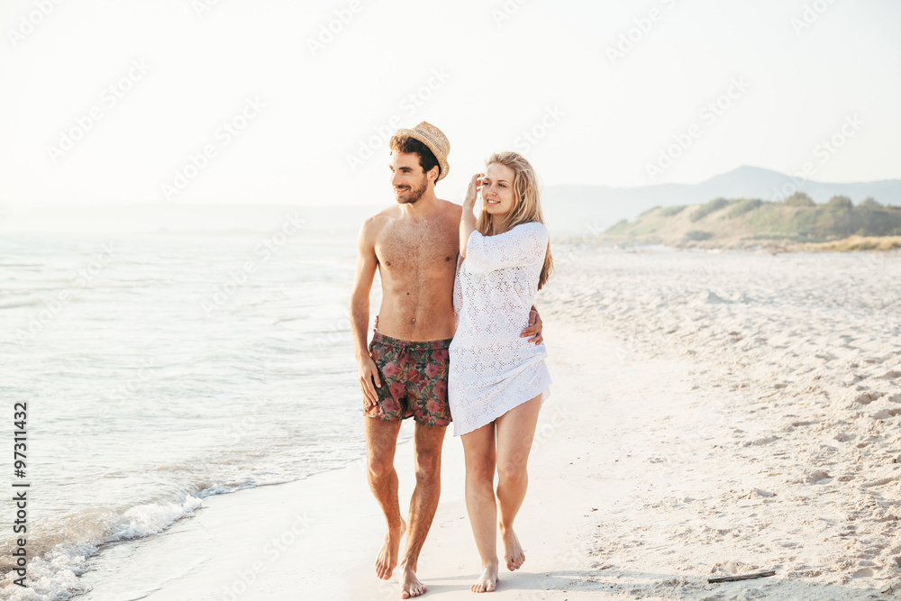 Sunset, sandy beach, a loving couple walks embraced on the deserted beach at sunset during a day at the beach on vacation Sunset, sandy beach, a loving couple walks embraced on the deserted beach at sunset during a day at the beach on vacation