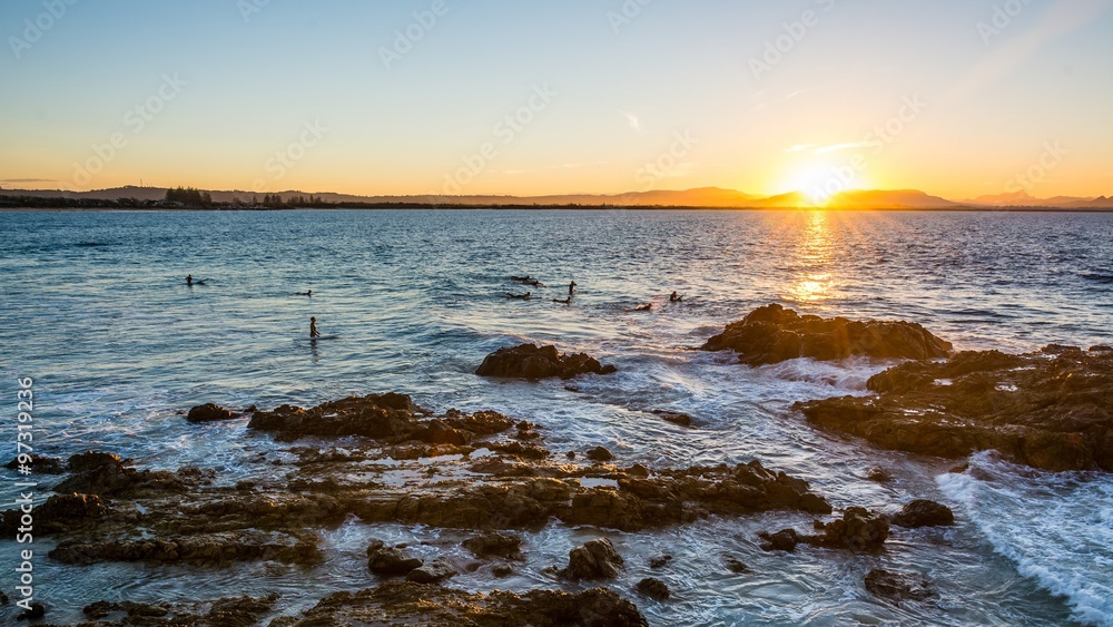 Obraz premium Surfer on waves in the sunset at byron bay