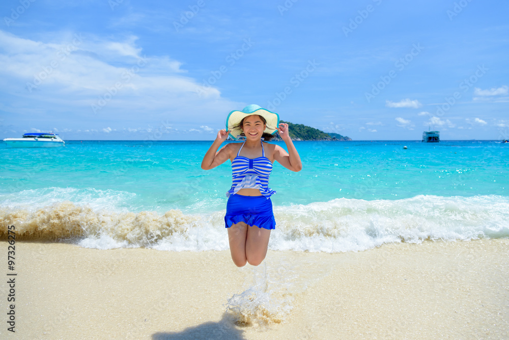 Tourist woman in a blue white striped swimsuit jumping with happy on the beautiful beach sea and sky during summer at Koh Miang Island, Mu Ko Similan National Park, Phang Nga, Thailand Tourist woman in a blue white striped swimsuit jumping with happy on the beautiful beach sea and sky during summer at Koh Miang Island, Mu Ko Similan National Park, Phang Nga, Thailand