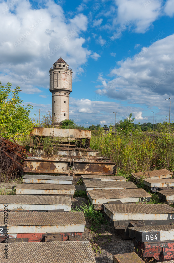 Abandoned water tower near old railway track with obsolete railway parts