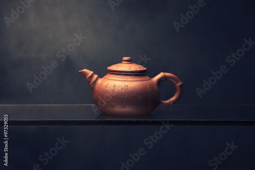 Chinese teapot with hieroglyphs on the glass on a dark background