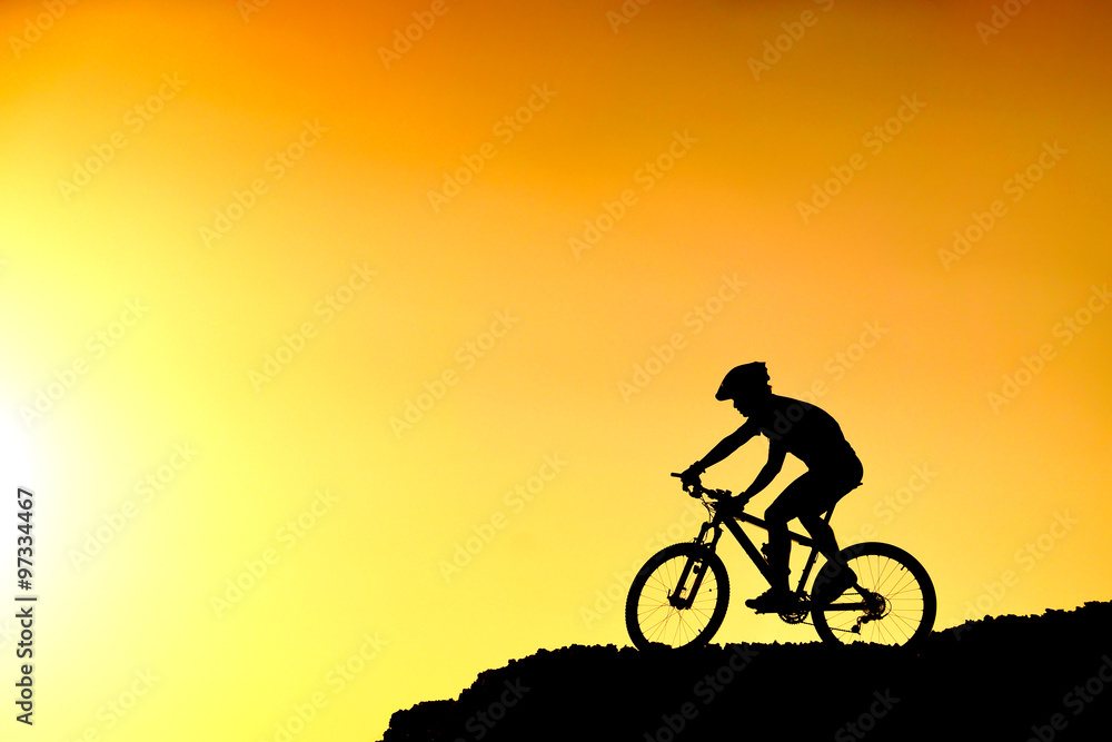 A cyclist riding down the hill with sunset silhouette