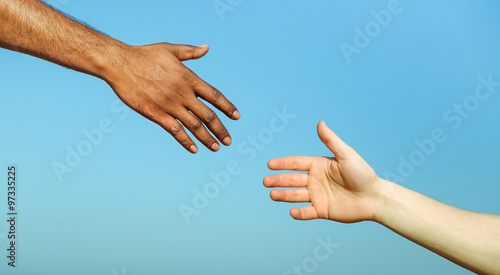 Black hand man helping white person - Different skin color hands united against racism and racial problem - Concept of humane aid between different cultures and religion - friendship between peoples
