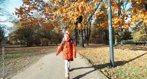 Schoolgirl running at the camera in the park in the autumn
