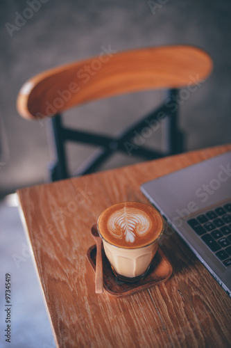 cup of coffee latte on the wood texture   in vintage color tone photo