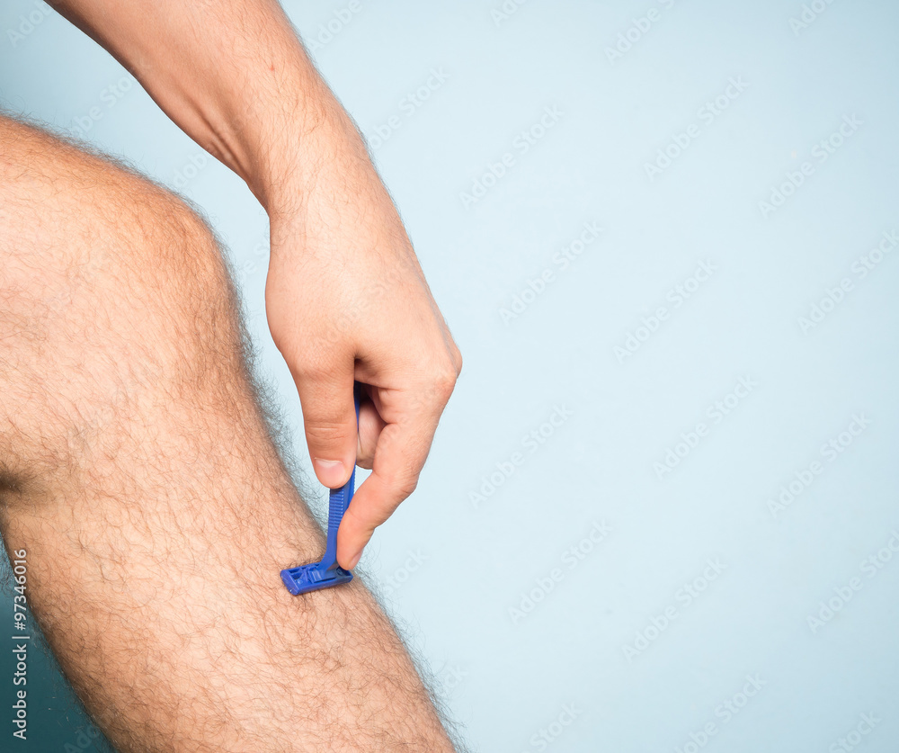 Fototapeta premium Caucasian man shaving hair from legs