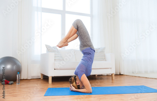 woman making yoga in headstand pose on mat