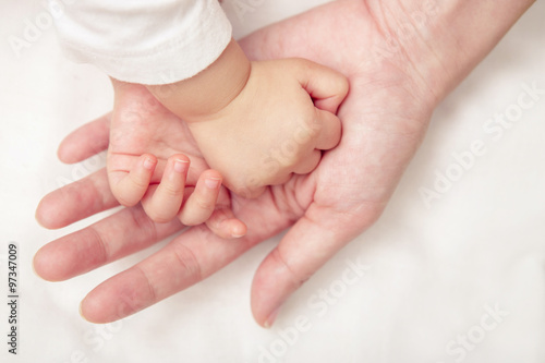 Baby hand gently holding adult's finger (Soft focus and blurry)